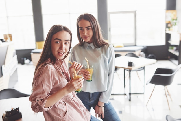 Deux belles filles jumelles passent du temps à boire du jus. Soeurs se détendre dans un café et s'amuser ensemble