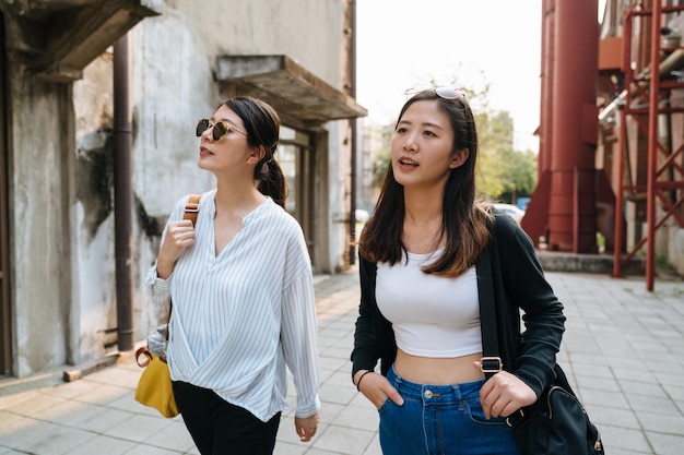 Deux belles filles marchant en été à l'extérieur visitent l'ancienne usine rouge. femme portant une chemise élégante et un jean bleu profitant d'une journée de congé et s'amusant avec un ami. monument touristique des femmes asiatiques