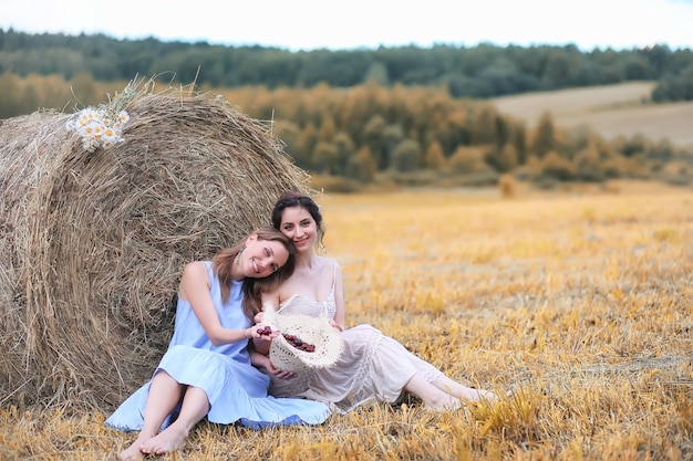 Deux belles filles en robes dans le champ d'automne avec des baies