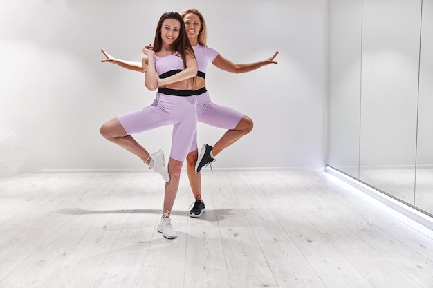 Deux belles filles s'étirent avant le cours de danse et regardent la caméra