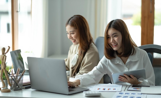 Deux belles jeunes femmes asiatiques travaillant au bureau sur un ordinateur portablexA