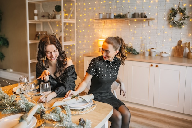 Deux belles jeunes filles joyeuses joyeuses ami rire de la table à manger de Noël sur le fond de la cuisine du nouvel an