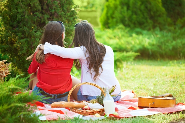 Deux belles jeunes filles lors d'un pique-nique en été dans le parc, s'amusant et discutant