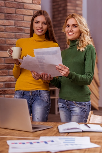 Deux belles jeunes filles tiennent une tasse et des documents.