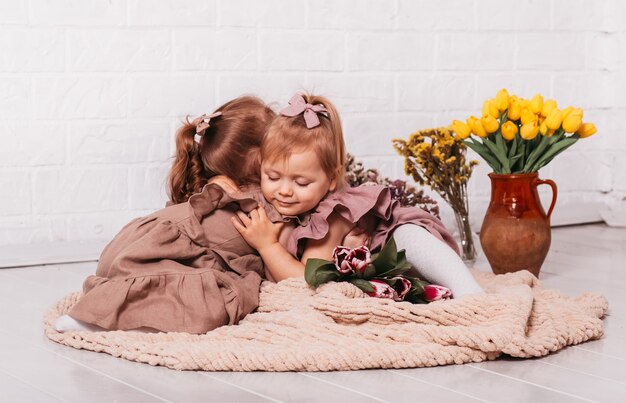 Deux belles petites filles câlins dans une chambre avec des fleurs