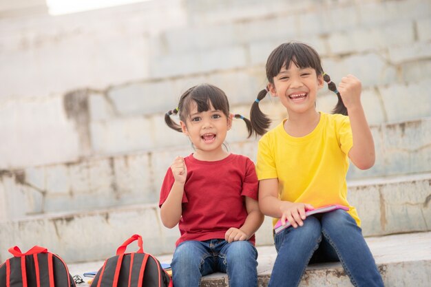 Deux belles petites filles lisant des livres dans le jardin, assises sur l'herbe. Le concept d'éducation et d'amitié.