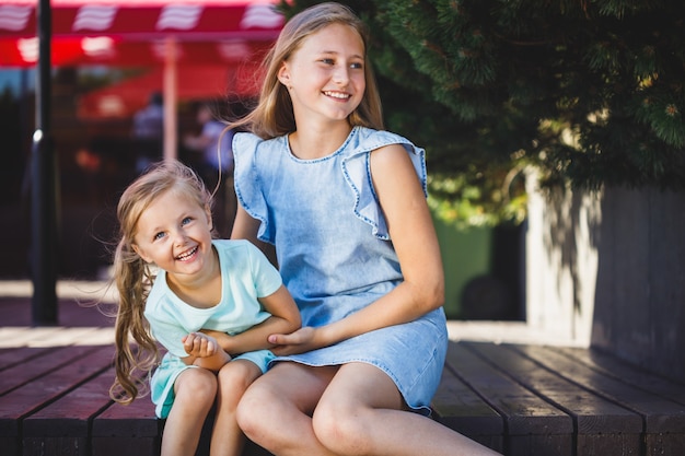 Deux belles soeurs s'asseyant chatouillant et riant en parc