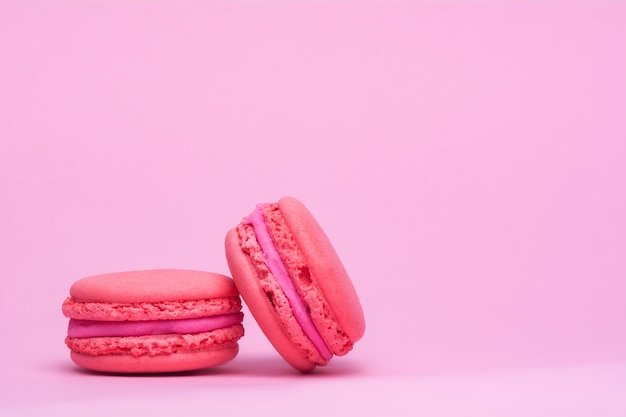 Deux biscuits macaron rose sur fond rose.