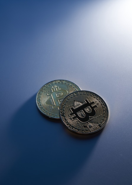 Deux bitcoins dorés isolés sur fond bleu en gros plan avec espace de copie, concept de croissance et chute de la crypto-monnaie