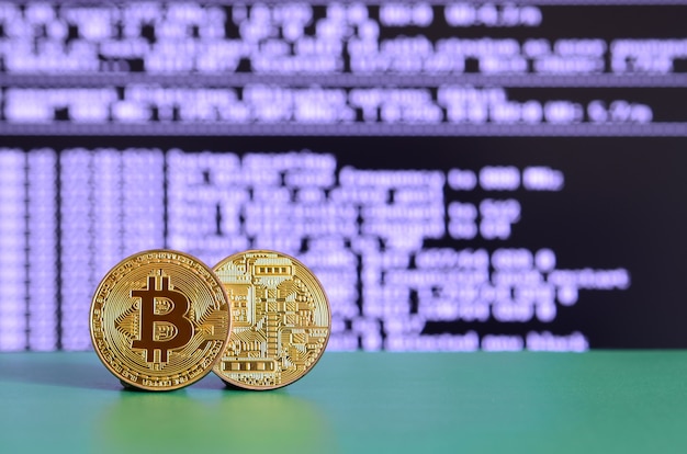 Deux bitcoins dorés se trouvent sur la surface verte à l&#39;arrière-plan de l&#39;écran