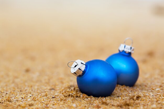 Deux boules de Noël bleues sur la rive sablonneuse de l'océan