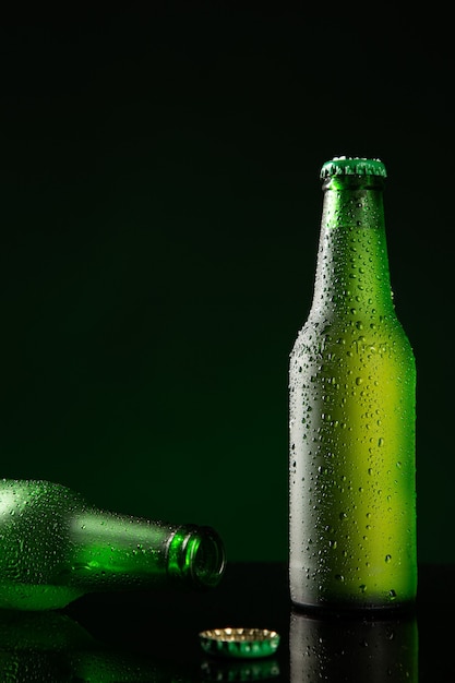 Deux bouteilles de bière froide avec goutte d'eau sur fond vert foncé avec copyspace. Format vertical.