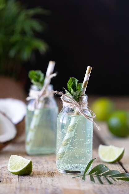 Deux bouteilles d'eau de coco à la menthe et au citron vert sur une table en bois. Boisson végétarienne. Mojito. Espace copie