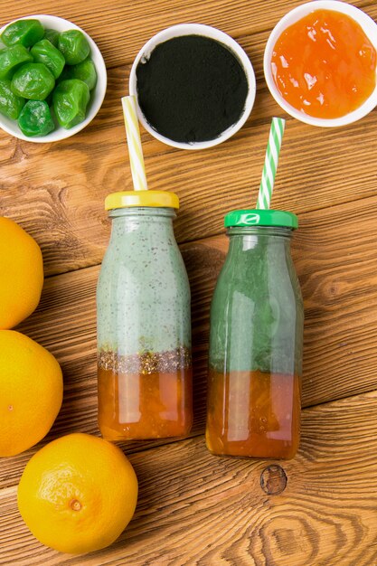 Deux bouteilles de smoothie avec de la spiruline, du yaourt et de la confiture à côté des ingrédients