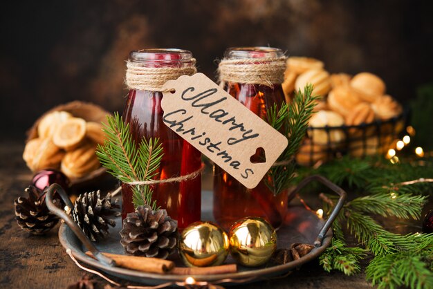 Deux bouteilles de vin chaud de Noël chaud aux épices sur un mur en bois.