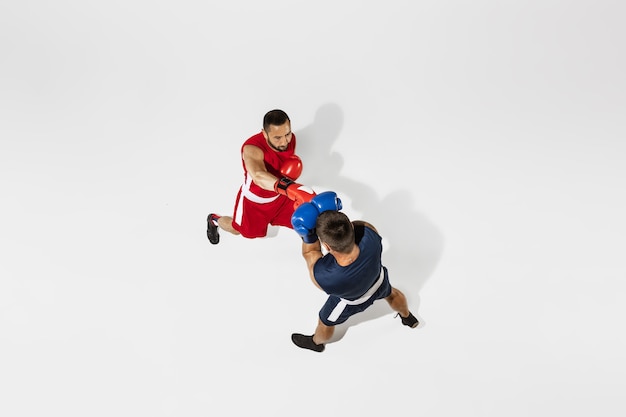 Deux boxeurs professionnels boxe isolés sur fond blanc studio, action, vue de dessus. Couple d'athlètes caucasiens musclés en forme qui se battent. Concept de sport, de compétition, d'excitation et d'émotions humaines.