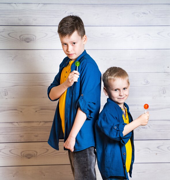 Deux brohers en t-shirts jaunes et chemises bleues avec des sucettes colorées