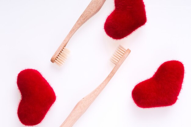 Deux brosses dentaires beiges avec des coeurs rouges sur blanc. Isolé. Amour. Saint Valentin.