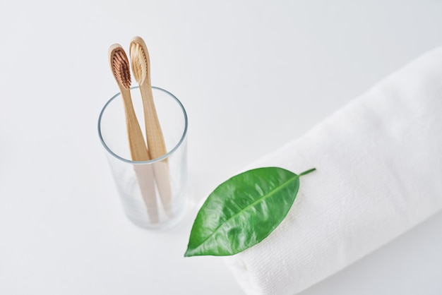 Deux Brosses à Dents En Bambou Respectueuses De L'environnement En Verre Et Serviette Sur Blanc.