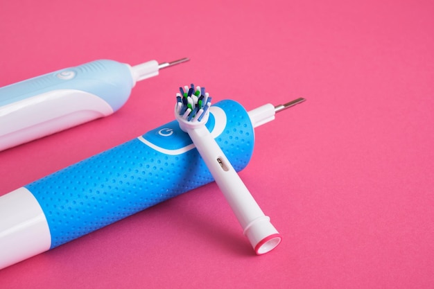 Deux brosses à dents bleu électrique sur fond rose vif brosse à dents électrique d'hygiène bucco-dentaire