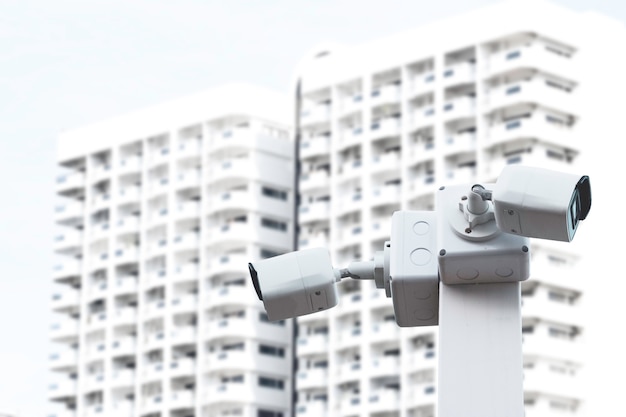 Deux caméras de vidéosurveillance blanches surveillant les actifs appartenant et le bâtiment au nom du gardien de sécurité.