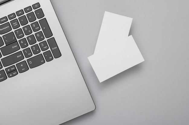 Deux cartes de visite blanches pour l'image de marque et un ordinateur portable sur fond gris Vue supérieure Concept d'entreprise
