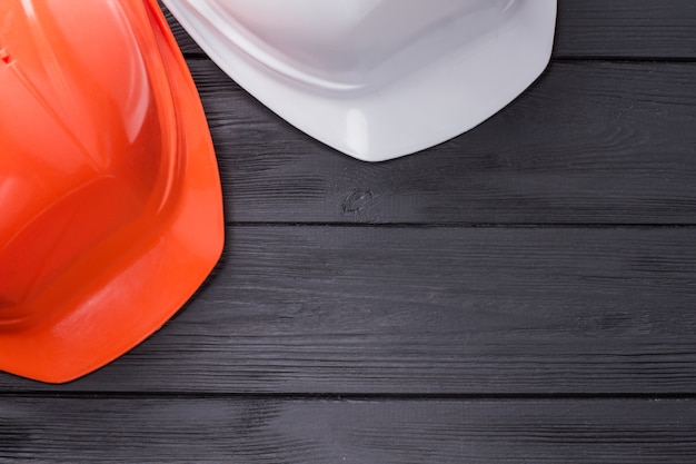 Deux casques de sécurité sur table en bois noir. Casques de constructeur blancs et orange et espace de copie.