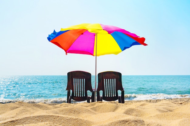 Deux chaises longues sous un parasol sur la plage