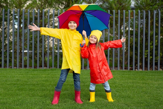 Deux charmants enfants un garçon et une fille jouent dans le parc avec un parapluie coloré