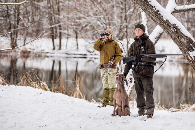 Deux chasseurs avec des fusils dans une forêt d'hiver enneigée