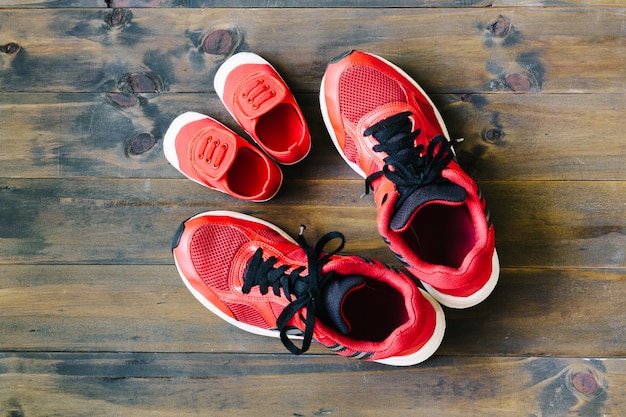 Deux chaussures de course de sport rouge ou espadrilles de mère ou père et enfant sur bois