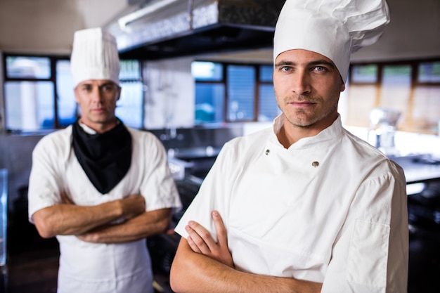 Deux chefs masculins debout avec les bras croisés dans la cuisine