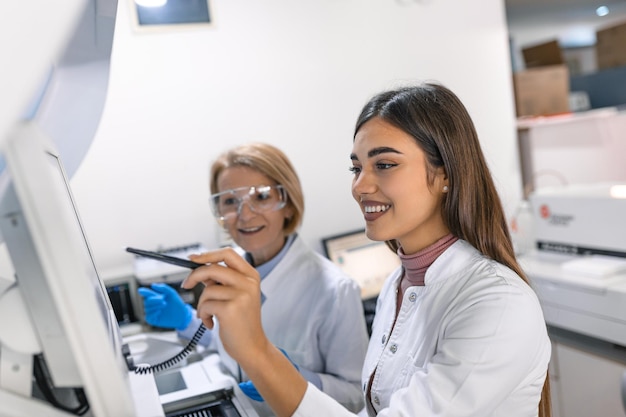 Deux chercheurs scientifiques discutent de la programmation d'équipements médicaux pour les tests Équipe de professionnels faisant de la recherche pharmaceutique dans un laboratoire moderne