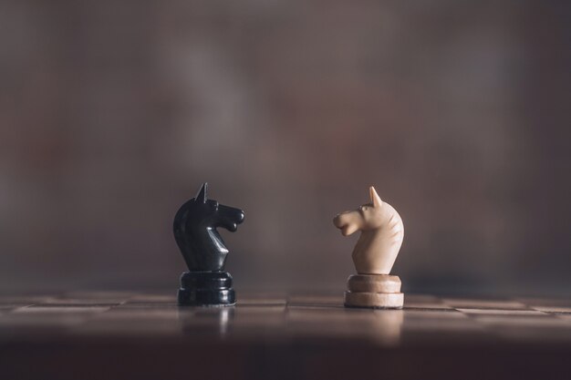 Deux chevaliers d'échecs blanc et noir debout en face de l'autre sur de vastes floues