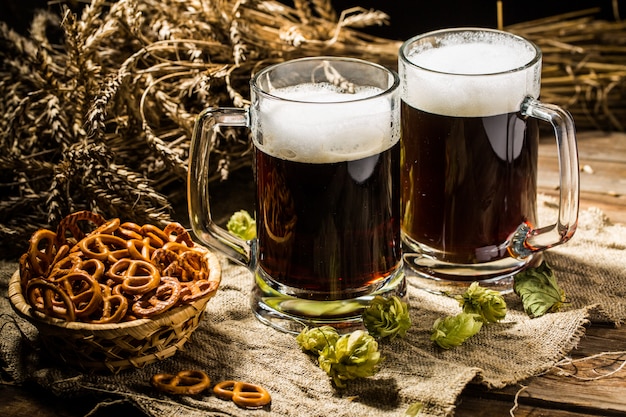 Deux Chopes De Bière Avec Du Blé Et Du Houblon, Un Panier De Bretzels