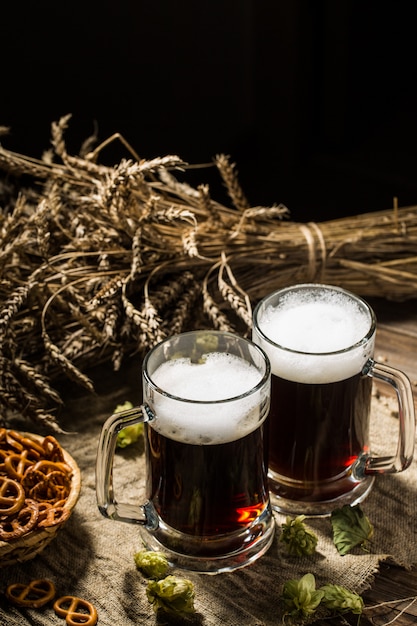 Deux chopes de bière avec du blé et du houblon, un panier de bretzels