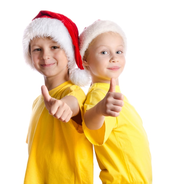 Deux cildl souriant avec thumbs up sign in Santa's hatts, isolated on white