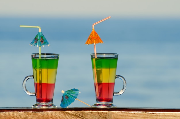 Deux cocktails avec des pailles sur le bar au bord de la mer au loin