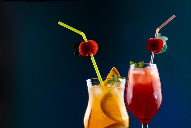 Deux cocktails tropicaux avec de la glace et des morceaux de fruits décorés de menthe et de tubes sur la table