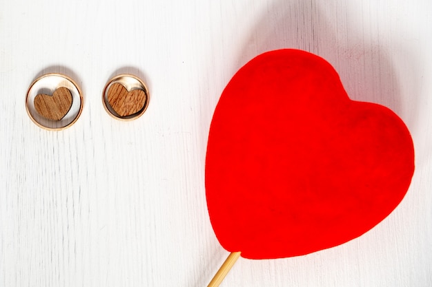 Deux coeurs en bois en anneaux d&#39;or de mariage paire avec coeur rouge sur fond blanc.