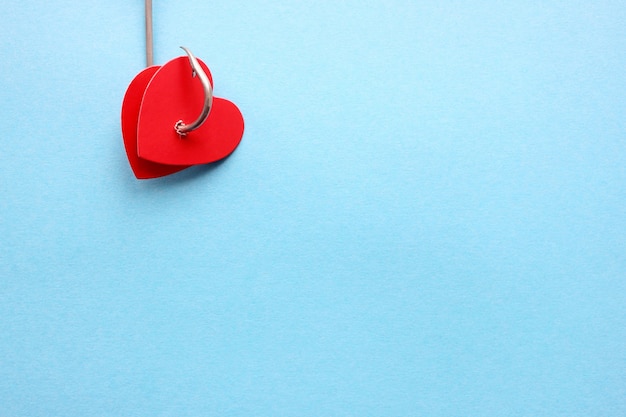 Deux coeurs rouges sur un crochet en métal sur fond bleu