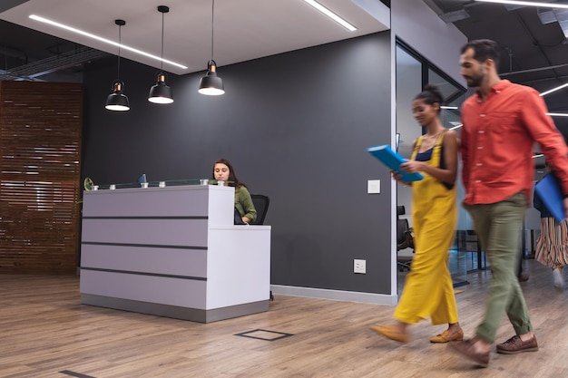 Deux collègues créatifs divers marchant en tenant des documents et souriant. bureau moderne d'une entreprise de design créatif.