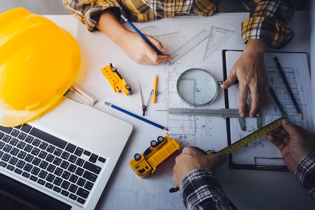 Deux collègues discutant du travail des données et d'un ordinateur portable avec une tablette sur un projet architectural sur un chantier de construction au bureau au bureau