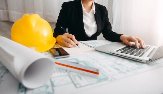 Deux collègues discutant du travail des données et d'un ordinateur portable avec une tablette sur un projet architectural sur un chantier de construction au bureau au bureau