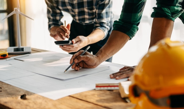 Deux collègues discutant du travail des données et d'un ordinateur portable avec une tablette sur un projet architectural sur un chantier de construction au bureau au bureau