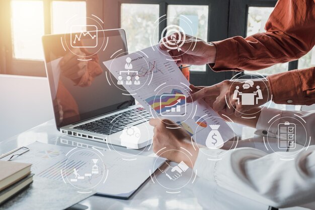 Deux collègues discutent de données avec un nouvel ordinateur portable moderne sur la table de bureau