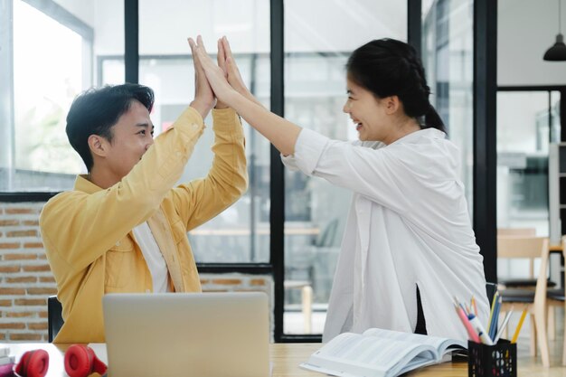 Photo deux collègues sympathiques et heureux donnant un high five au bureau célébrant le succès bonne coopération résultat partenariat travail d'équipe et motivation d'équipe dans le travail de bureau