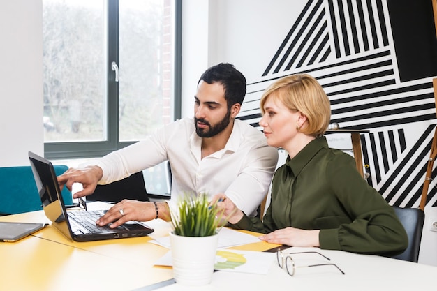 Deux collègues de travail travaillent avec un ordinateur portable dans un intérieur de bureau élégant