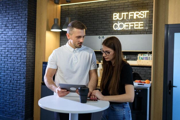 Deux collègues travaillent pendant une pause-café avec une tablette