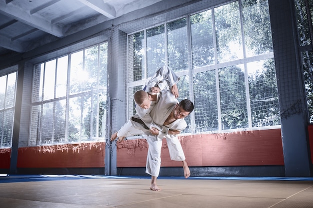 Deux combattants de judo montrant des compétences techniques tout en pratiquant les arts martiaux dans un club de combat. Les deux hommes en uniforme. combat, karaté, entraînement, arts, athlète, concept de compétition